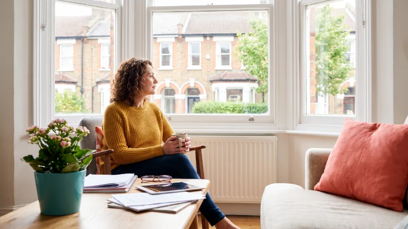 living room in the United Kingdom  featuring a cluttered coffee table with scattered documents, a laptop displaying a spreadsheet of financial figures, and a half-empty mug of tea,